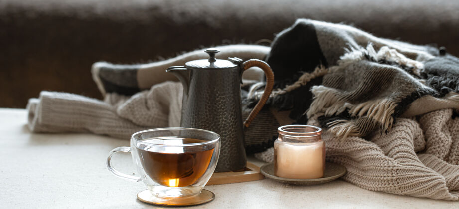 玻璃一杯茶 一个茶壶 烛台上的一支蜡烛 还有一个编织的东西茶壶房子烛台