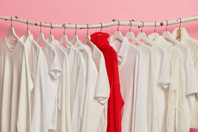 白色在时装店的衣架上可以选择白色的衣服红色明亮的针织毛衣在同一色调的衣服之间 隔离在粉红色的墙上水平时尚精品店