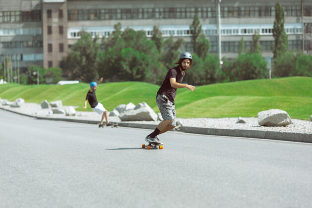 男孩在阳光明媚的日子里 滑板运动员在城市的街道上玩花样男子滑板公园危险