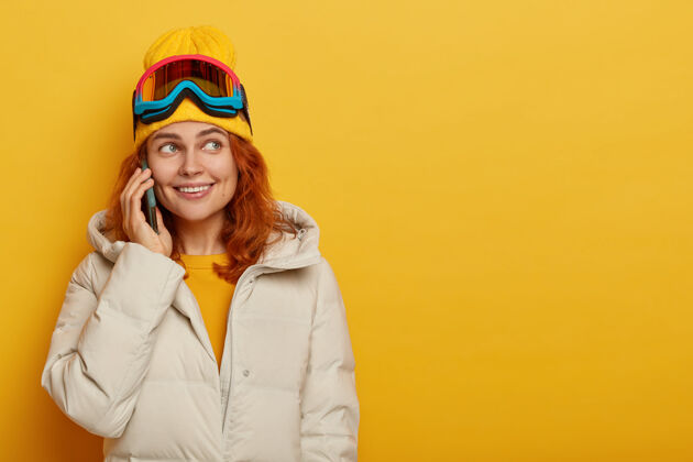 黄色横拍了一位滑雪者微笑着打电话给亲戚 讲述她的寒假 戴着滑雪镜说话运动说话
