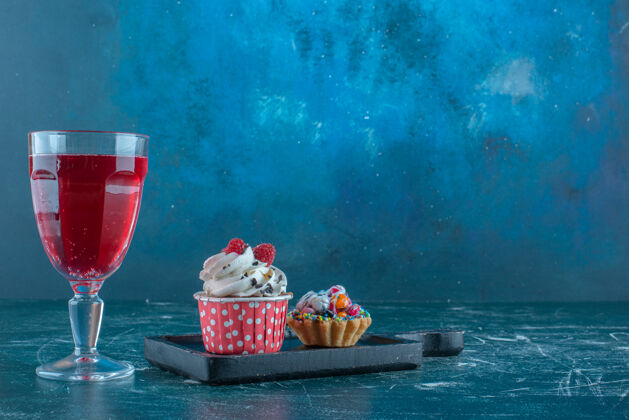 饮料一个果汁杯旁边的蓝色背景纸杯蛋糕高品质的照片糖果汁美味