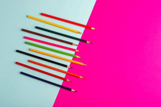 视图顶视图彩色铅笔衬在蓝色和粉色书桌彩色绘画艺术颜料教育彩虹线条