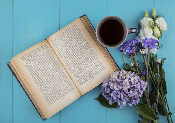 空打开的书的顶视图 蓝色背景上有一杯咖啡和鲜花杯子打开蓝色