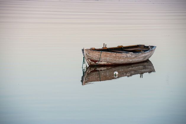 山一个老木船在反射湖面上的惊人镜头船平静倒影