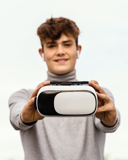 中镜头拿着虚拟现实眼镜的中镜头男孩创新未来设备
