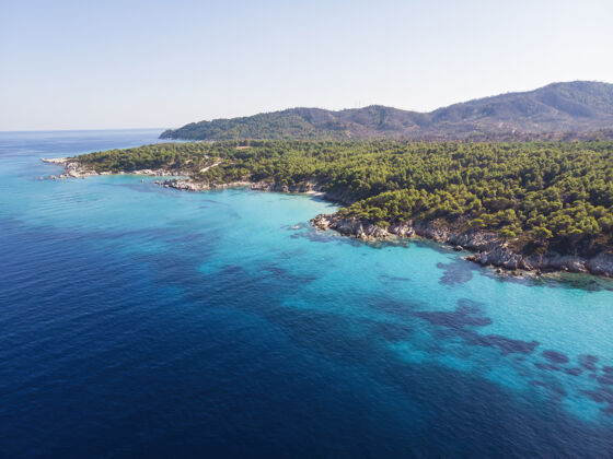 海洋爱琴海沿岸有蓝色透明的海水 周围绿树成荫 岩石 灌木丛和树木 从无人驾驶飞机上俯瞰希腊希腊山海