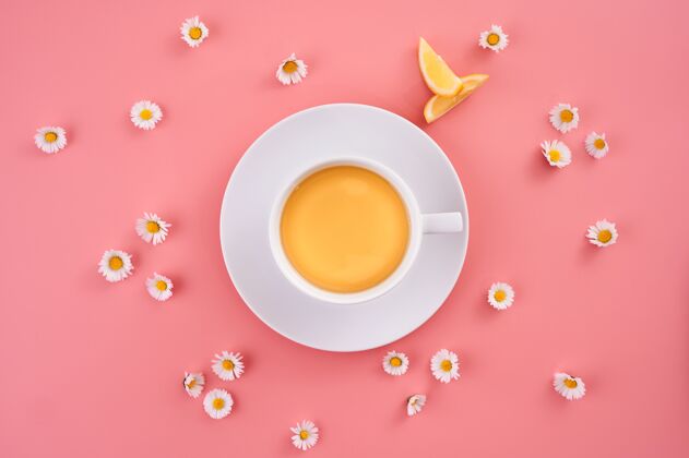 切高角度拍摄的一杯橙汁周围的小雏菊花粉红色的表面食物鸡尾酒成熟