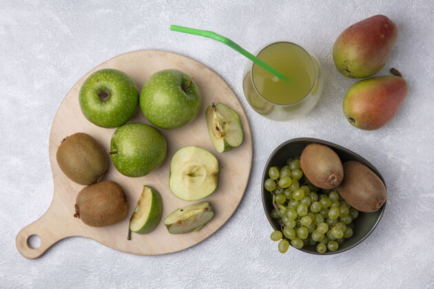 碗顶视图：梨子 猕猴桃和葡萄放在碗里 绿色苹果片放在架子上 苹果汁放在白色背景上甜点甜品切片