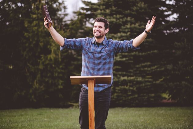 木头年轻的男人站着 手里拿着圣经手臂演讲年轻人