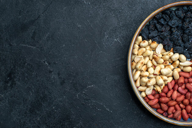 葡萄干顶视图榛子和葡萄干和其他坚果对深灰色办公桌坚果零食干果照片烤的种子豆类