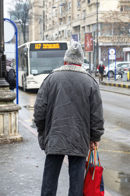 衣服一位身穿夹克 头戴羊毛帽子的老人停在路边 背景是街道 罗马尼亚布加勒斯特多云的天气罗马尼亚围巾罗马尼亚