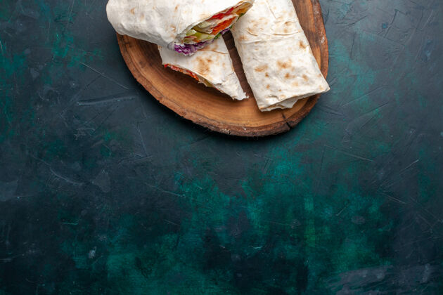 自制俯视图肉三明治一种三明治 由烤肉和蔬菜做成 放在深蓝色桌子上 三明治汉堡 午餐 肉生的景观肉