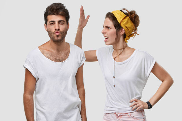 衣服愤怒的年轻女性头戴黄色头带 穿着休闲的白色t恤 举手走近丈夫 表情消极 要求不要装傻 有一些误解或争吵手势女人争吵