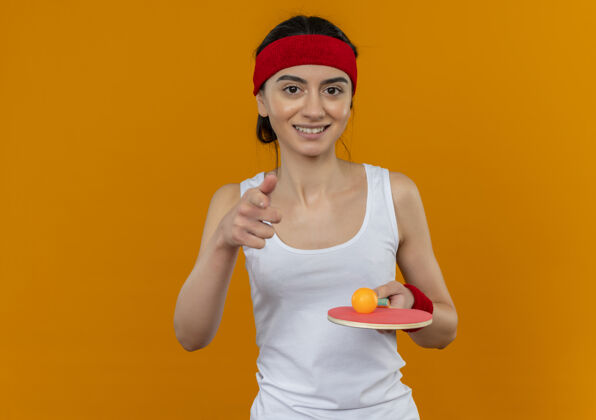 人身穿运动服的年轻健身女 头戴头巾 手持乒乓球和球拍 脸上洋溢着幸福的笑容网球快乐运动
