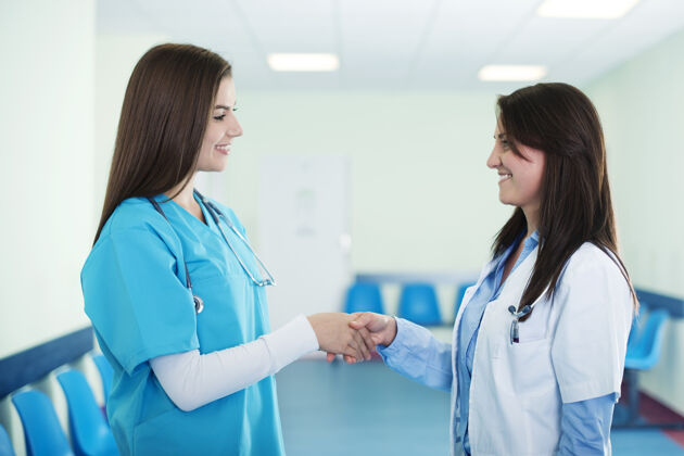 年轻女性医生在医院握手年轻人健康的生活方式制服