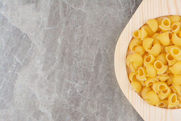 晚餐把生的意大利面放在大理石上的木盘里极简传统美味