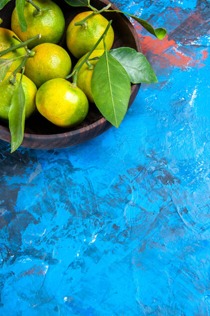 柑橘顶视图黄色橘子与树叶在木制碗蓝色表面与自由的地方叶子碗顶部
