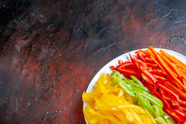 晚餐顶视图彩色切辣椒在白色盘子上暗红色的桌子与复制空间景观顶部盘子