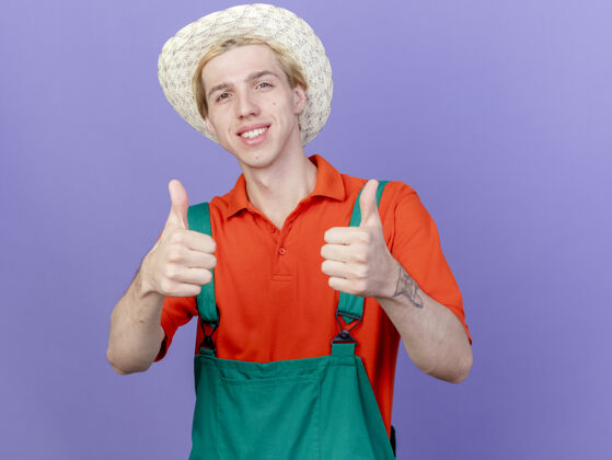 连身衣年轻的园丁 穿着连体衣 戴着帽子 脸上带着微笑帽子穿着相机