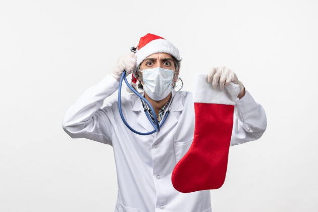 病毒正面图男性医生在观察白色地板上的节日袜子柯维德病毒假日健康男医生肖像冠状病毒