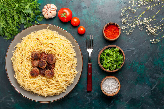 意大利面酱汁俯视图煮熟的意大利面食与肉丸调味料和绿色的深蓝色表面午餐生的一餐