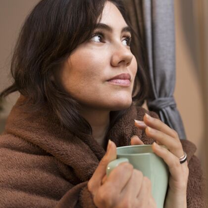 女性一个拿着一杯咖啡 身上裹着毯子的年轻女人海格斯堪的纳维亚风格生活方式