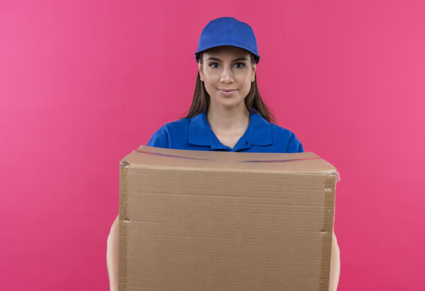 粉色身穿蓝色制服 头戴帽子的年轻送货女孩拿着大礼盒 神情严肃自信地看着镜头表情制服包装