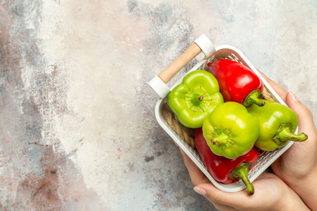甜椒顶视图绿色和红色辣椒在塑料篮在女性手上裸体表面与自由空间吃苹果篮子塑料