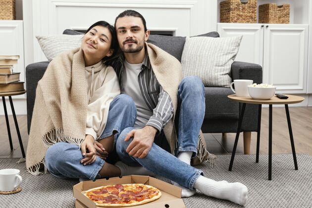 休闲一对穿着毛毯看电视吃比萨饼的夫妇享受情侣看电视