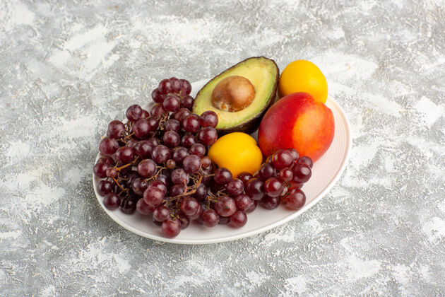 甜正面图新鲜水果 葡萄 桃子和鳄梨在白色的盘子里浆果健康正面