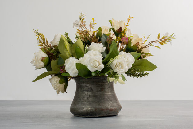 叶美丽的白玫瑰花束放在灰色的桌子上安排花束视图