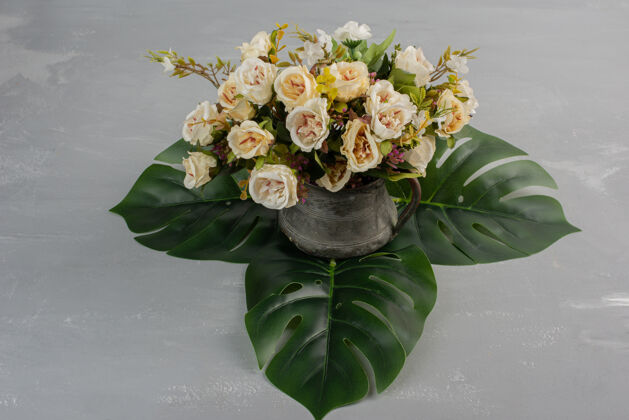 视图美丽的白玫瑰花束放在灰色的桌子上叶安排花