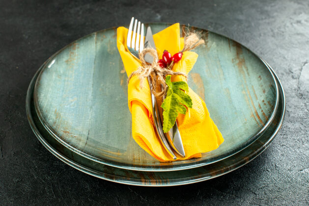 午餐底图黄色餐巾纸刀叉用绳子绑在黑色桌子上的盘子上刀晚餐叉子