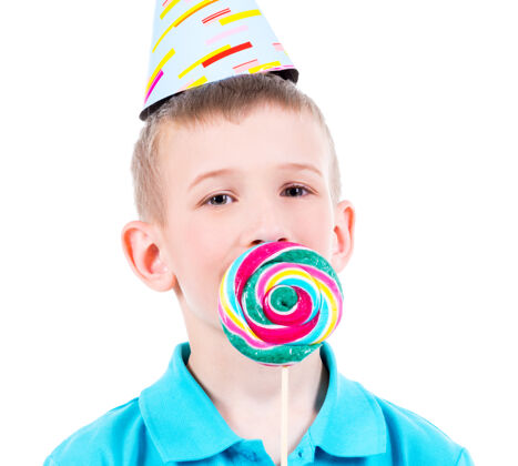 糖果微笑的男孩穿着蓝色t恤 戴着彩色糖果的派对礼帽-白色隔离甜食帽子游戏