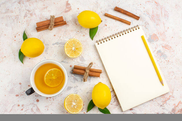 记事本顶视图新鲜柠檬切柠檬肉桂棒一杯柠檬茶笔记本上明亮的隔离表面切割肉桂鸡蛋