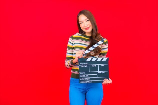视频在红色的隔离墙上用电影石板画出美丽的亚洲年轻女子工业板岩场景