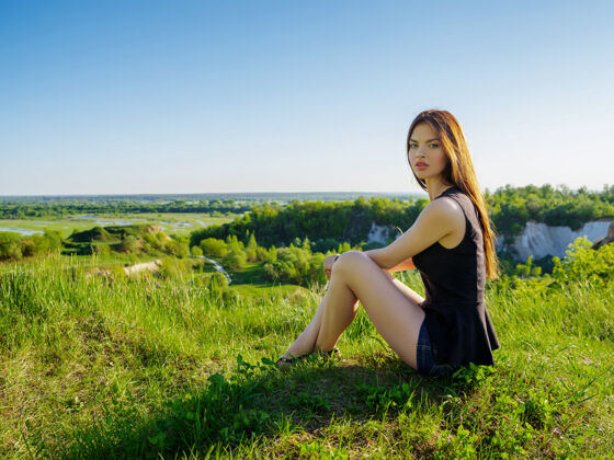 春天美丽的长发女孩在户外放松坐在悬崖边的年轻女子在大自然中在一个阳光明媚的夏日 女模特在田野里摆姿势女人自然年轻