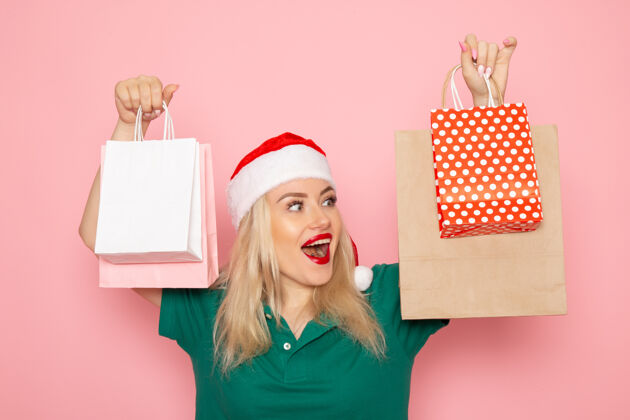 风景正面图：年轻女性手拿圣诞礼物 包装在粉红色的墙上 圣诞照片模特新年包装年轻女性肖像