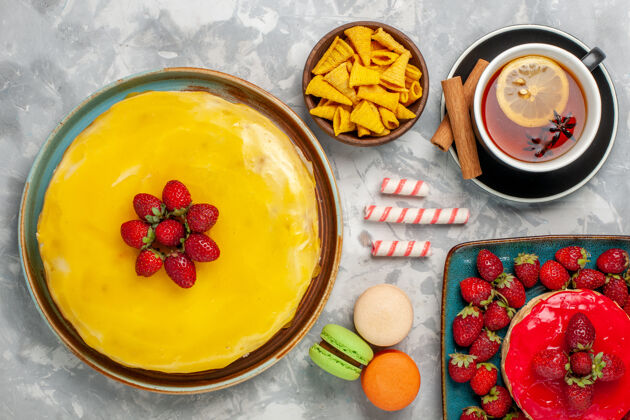 甜食俯视图黄色蛋糕 白色背景上有草莓蛋糕和一杯茶盘子蛋糕托盘