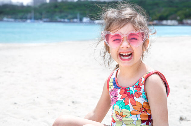 大海有趣的小女孩戴着太阳镜在沙滩上玩沙子夏日娱乐和休闲小坐欢乐