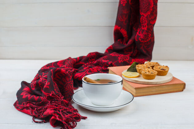 咖啡特写镜头：一杯茶 一盘白饼干 一条红围巾和一本书食物饼干盘子