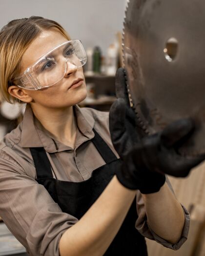 工人带安全眼镜的女木匠正在检查锯片劳动者贸易女人