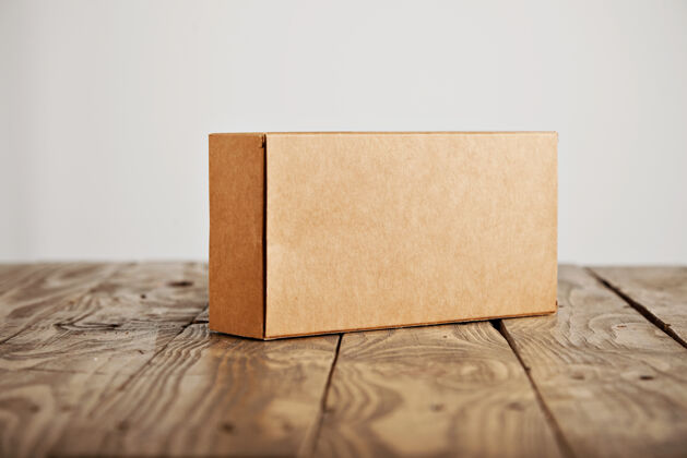 空的工艺无标签纸板包装盒呈现在强调拉丝木桌上 隔离在白色背景上消费主义打开礼品