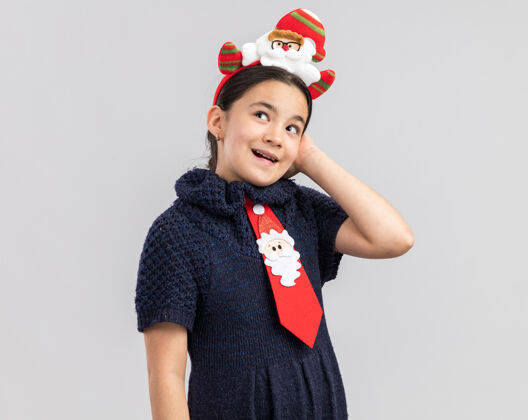 衣服小女孩穿着针织连衣裙 头上系着一条红色领带 上面戴着一个有趣的圣诞戒指 看上去很开心 很积极积极年圣诞快乐