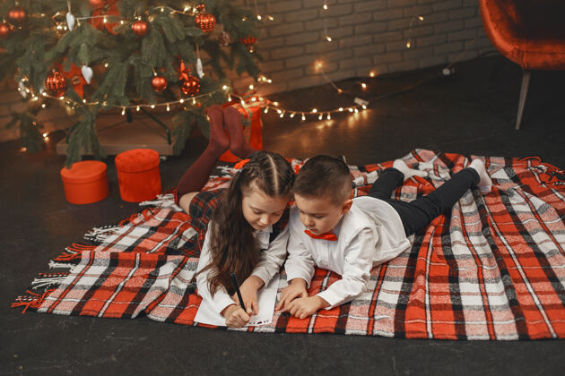 快乐孩子们坐在圣诞树旁孩子们给圣诞老人写信女儿室内圣诞树