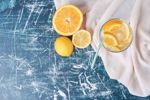 热柠檬橙子和一杯饮料放在蓝色上点心产品质量