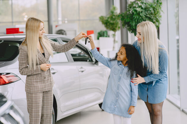 汽车一家人在汽车沙龙里买车的女人和妈妈在一起的非洲小女孩和客户在一起的经理展厅非洲人