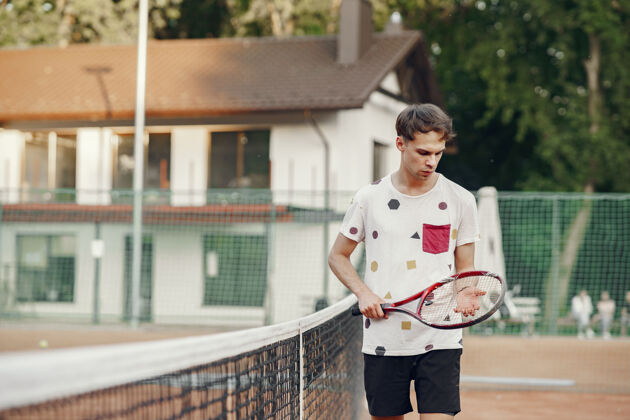 人今天玩得很开心 穿着t恤的年轻人手里拿着网球拍和球的家伙男性比赛休闲