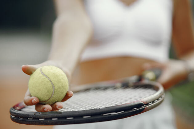 金发今天玩得很开心 穿着t恤的年轻女子拿着网球拍和球的女子户外网球休闲