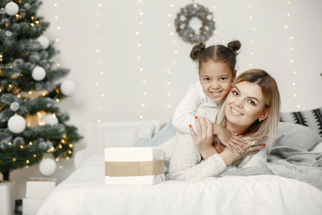 花环人们在为圣诞节做准备母亲在和女儿玩耍一家人在节日的房间里休息孩子穿着毛衣装饰圣诞树阳光